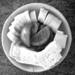 ein Frühstücksteller mit Gurkenscheiben, Tofu, Tomaten und Kräutersalz